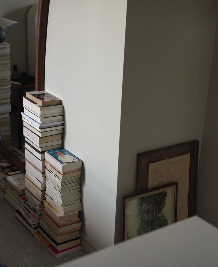 Stack of books as side table, art leaning on the floor, Art of an unfinished home