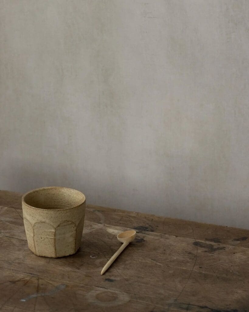Antique or vintage wood table with yellow ceramic cup and wooden spoon